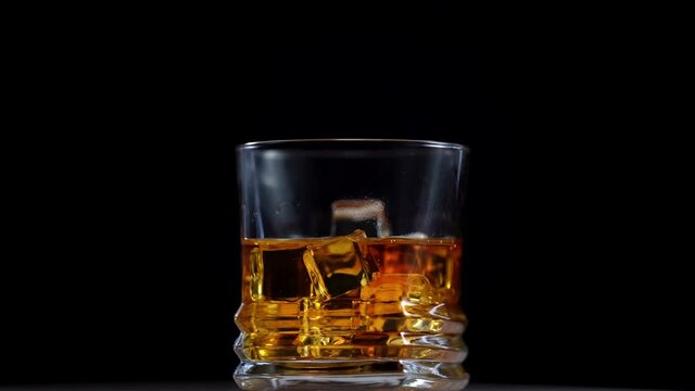 Whisky is poured into glass in slow motion. Rotation glass