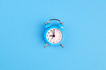 Classic alarm clock on blue background. Top view, copy space.