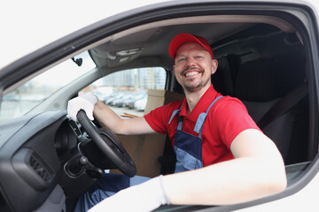 Smiling courier driver sits behind wheel of car