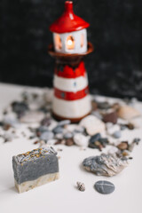 A small decorative lighthouse with sea shells and pebbles. Summer, holidays and vacation concept