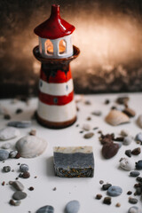 A small decorative lighthouse with sea shells and pebbles. Summer, holidays and vacation concept