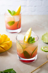 Summer mango refreshment cocktail made with fresh mango juice, ice cubes and mint leaves. Pink cocktail with fruit