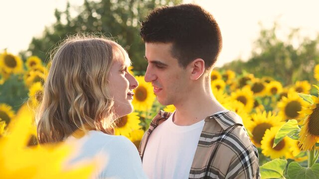Pareja alegre celebrando sus vacaciones de verano en un campo de girasoles 