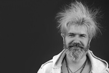 Goofy young man, with full beard and moustache and wild hair, pull a comical face to the camera....