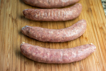 Fresh raw Italian sausages on a wooden kitchen board close up shot top view no people