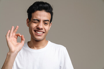Brunette hispanic man in t-shirt winking and gesturing at camera