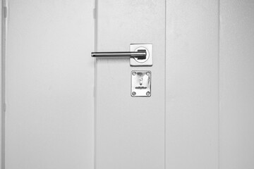 Shiny metal handle in a white closed door to an office, laboratory, study. Keyhole. Minimalism, laconic concept.