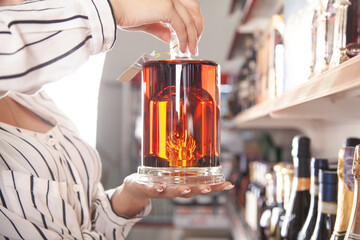 Woman buying cognac at supermarket.