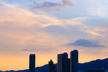 Fototapeta na wymiar タイトル : 日の入り前の六甲山。西の空と雲がオレンジ色に染まるマジックアワー。高層ビルがシルエットで浮かぶ。１日の終わり。