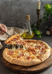 selective focus. hot pizza with cheese and pepperoni. the girl pulls a slice of pizza with melted cheese stretching. vertical position, dark mood