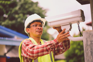 Technician installing IP  wireless CCTV camera installing security equipment water proof cover to...