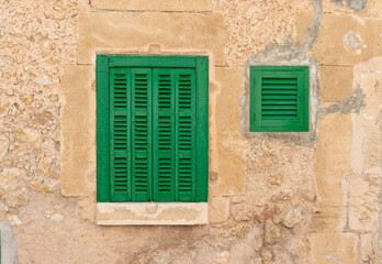 Closeup shot of green windows on an exterior wall of an old building