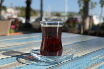 Turkey - Kas - Glass of Turkish Tea on a weathered wooden blue table.
