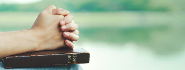 Hands folded praying over a Bible, hands over soft focus Bible.For banner.Holy Bible in church concept for faith, spirituality,worship and religion.