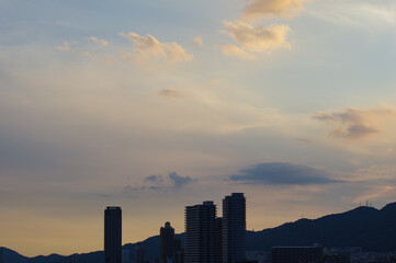 Fototapeta na wymiar 日の入り前の六甲山。西の空と雲がオレンジ色に染まるマジックアワー。高層ビルがシルエットで浮かぶ。１日の終わり。