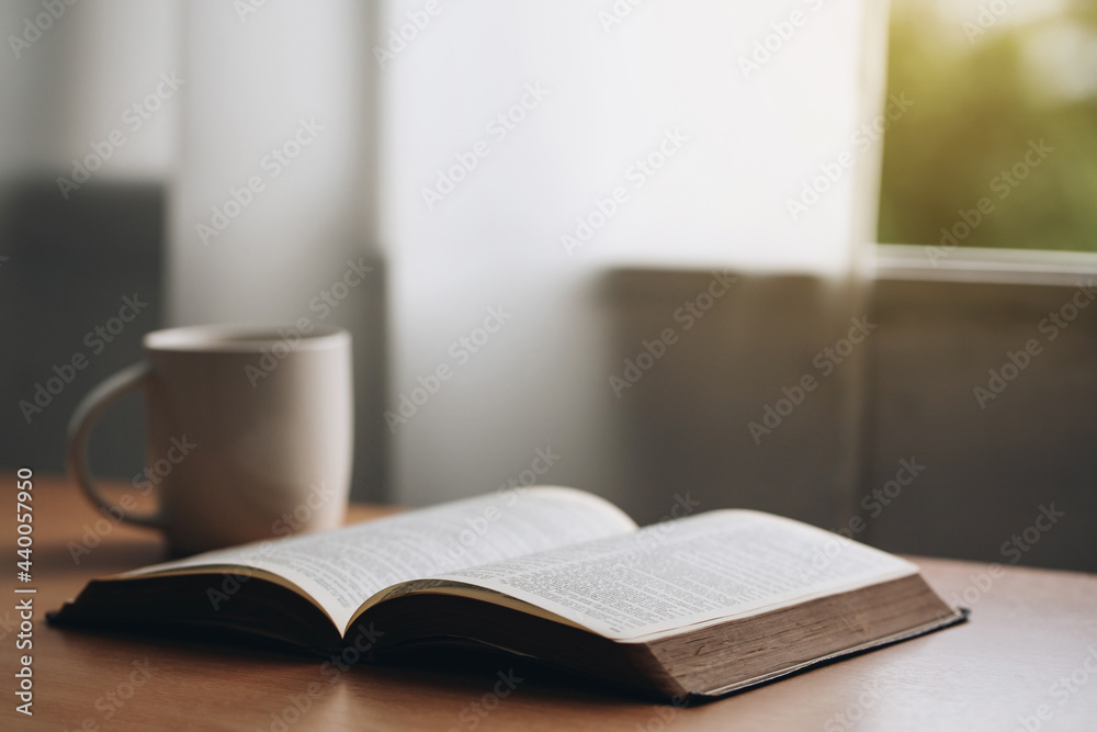Wall mural open bible with a cup of coffee for morning devotion on wooden table with window light.book and coff - Wall murals