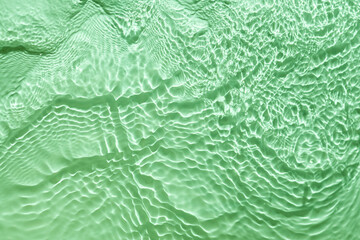Naklejka na ściany i meble Surface of cosmetic moisturizer splash reflections on scattered sun. light green abstract background
