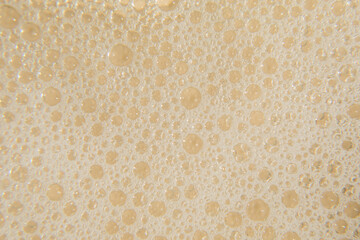 White cosmetics foam texture on beige background. Cleanser, shampoo bubbles, wash - liquid soap,...