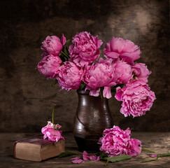 Beautiful bouquet of pink peonies in vase and old book