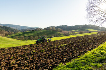 Pflücken des Acker im März mit Traktor  und Pflug. - obrazy, fototapety, plakaty