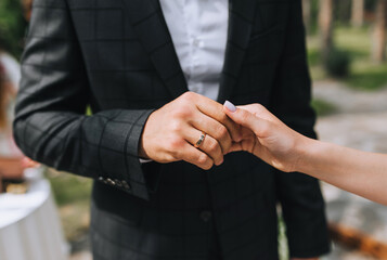 The groom at the wedding ceremony holds the bride's hand with a gold ring close-up. Photography, concept.