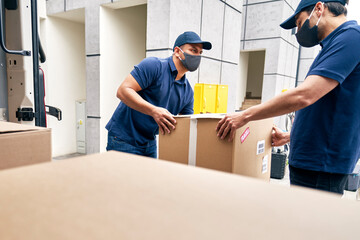 Couriers unloading packages from a delivery truck during a pandemic