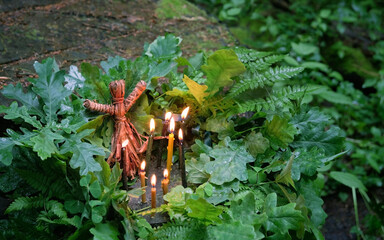 magic witchcraft doll made of tree bast, burning candles, oak and fern leaves, natural background....