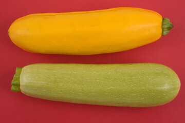 Courgettes blanches Lorea et courgettes jaunes crues sur fond rouge