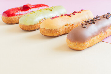 Eclairs on a minimal background. Still life hello dessert mood. Traditional French dessert with colorful icing. Concept baking, cookbook recipes, bakery banner, cafe advertisement.