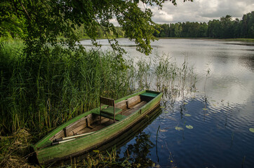 Fototapeta na wymiar Boat in Kazdanga village mill lake, Latvia.