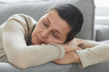 Candid close up of mature woman sleeping on sofa at home in cozy and calm setting, copy space