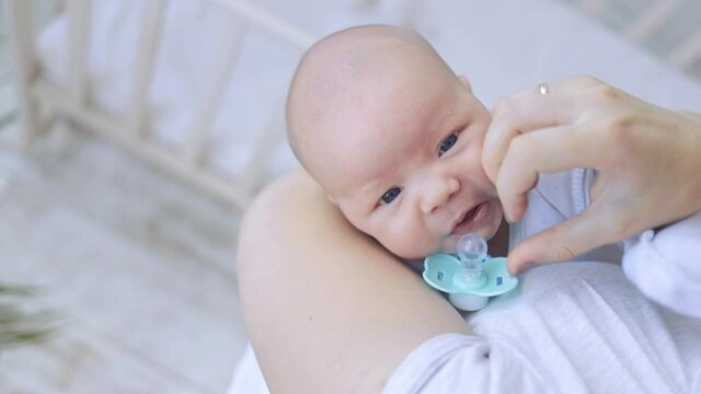 mom cradles and calms the capricious baby in her arms with a pacifier, the newborn falls asleep