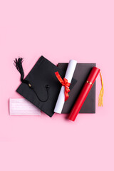Graduation academic cap with diploma and mask isolated on pink table background.