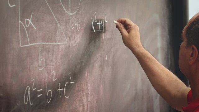 teacher man hand writing mathematical equations on a chalkboard. education concept