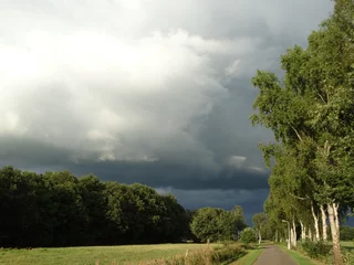 Fototapeten Thunder clouds. Dramatic dark sky in green summer landscape. Panoramic view on thunderstorm. Background. Onweerswolk. Code geel. Code oranje. Dreigende wolk boven groen zomer landschap. © Stobbe