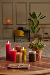 Colorful candle close up concept with coffee wicker glass on the wooden desk, decorative working table computer and chair lamp background.