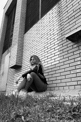 Hipster girl sits on a brick wall background.