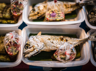 Grilled mackerel in styrofoam boxes for sale on carts in Naklua Market, Thailand.