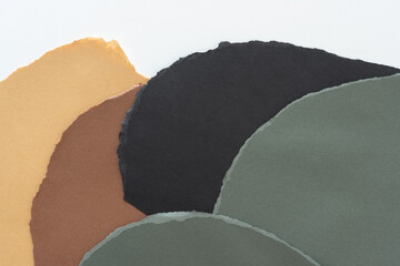 layered grey black brown and ochre yellow or sand brown torn construction paper on white