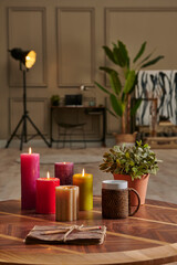 Colorful candle close up concept with coffee wicker glass on the wooden desk, decorative working table computer and chair lamp background.