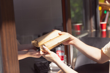 Hands close up giving order at mobile snack bar outdoors. Fresh, food, street, city lifestyle concept.