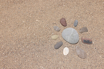 Fototapeta na wymiar Stones lying on sand in shape of sun closeup background