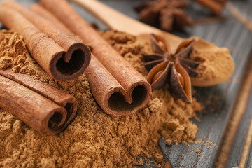 Obraz na płótnie Canvas Cinnamon sticks and powder on wooden background, closeup