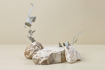 Abstract scene with composition of stones and eucalyptus leaves. Neutral beige podium background...