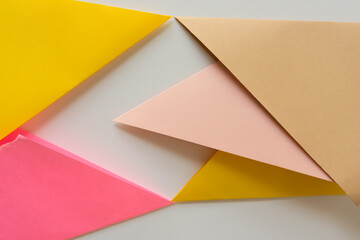triangle-shaped folded construction paper background in sand pink yellow on white