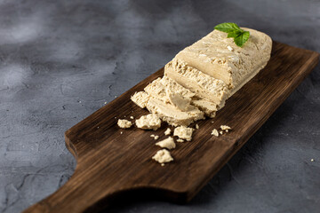 Slices of halva on cutting board. Sweet dessert with mint leaves on black background