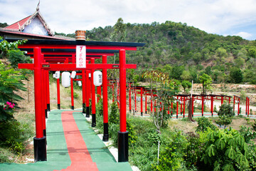 Fototapeta na wymiar Red torii gate of Wat Khao Sung Chaem Fa temple on Khao Sam Sip Hap mountain for thai people and foreign travelers travel visit and respect praying at Tha Maka on May 23, 2021 Kanchanaburi, Thailand