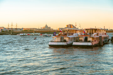 Fototapeta premium Panoramic view of the beautiful sunset over the Neva River in St. Petersburg and pleasure boats with tourists. Saint Petersburg, Russia - 05 Apr 2021
