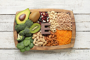 Board with healthy products rich in vitamin E on light wooden background - obrazy, fototapety, plakaty