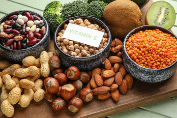 Board with healthy products rich in vitamin E on color wooden background, closeup